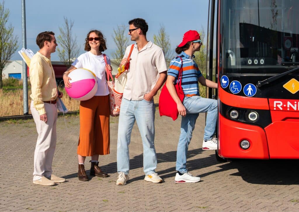 Four beachgoers with beach gear board the Strandbus on their way to Zandvoort Beach.