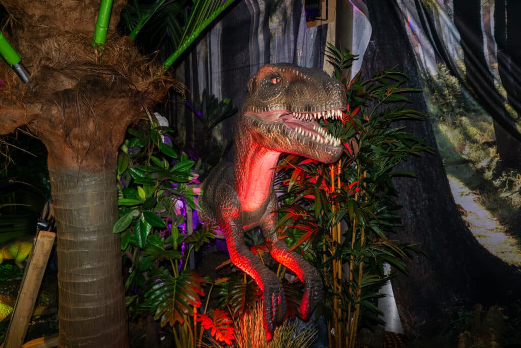 Animatronic Velociraptor among tropical plants and trees at the indoor dinosaur attraction World of Dinos in Zandvoort.